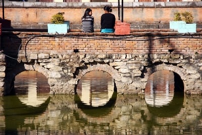 BUILDING BRIDGES: Two women sit and chat on a bridge in Patan on Friday.
