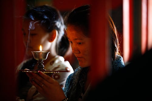 Daughter of Ang Kaji Sherpa, one of the 16 mountaineering guides killed in last year's Everest avalanche, lights a lamp in memory of her father at a monastery in Kathmandu on Saturday.