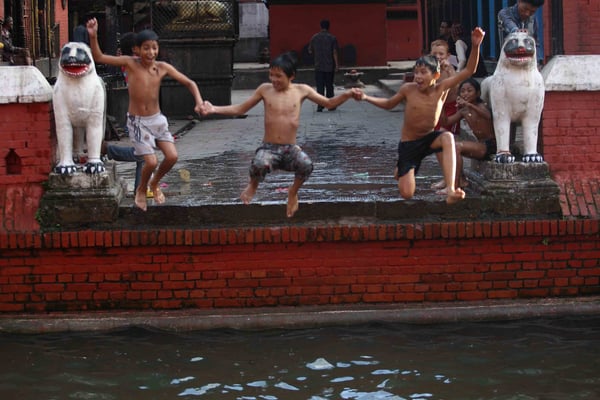 Three boys jump into a pond near Bangalamukhi temple at Lalitpur on Monday.