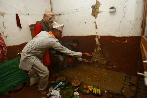 A priest plants barley seeds on the occasion of Ghatasthapana inside an earthquake-damaged building at Basantapur Darbar Square on Tuesday. Barley or Jau is planted to produce jamara (malt sapling) that is used on the seventh day of Dasain.