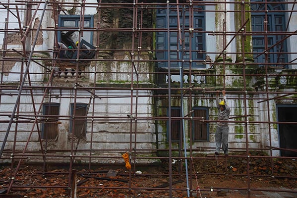 Workers climb supporting rods to place a tarp over an earthquake damaged structure at Basantapur Darbar Square on Saturday.