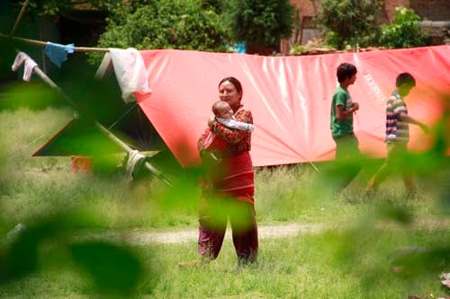 A woman carries her baby outside a temporary shelter in Bhaktapur on Sunday.