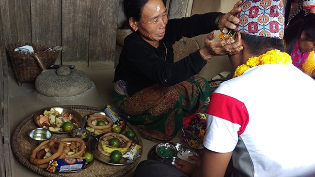 60-year-old Chig Kumari Gurung applies tika to her cousin brother's forehead on Bhai Tika in Ghanpokhara, Lamjung.