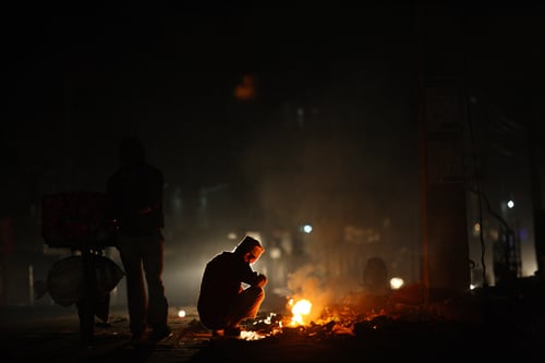 A man keeps himself warm by starting a bonfire at Kuleshwor on Sunday morning.