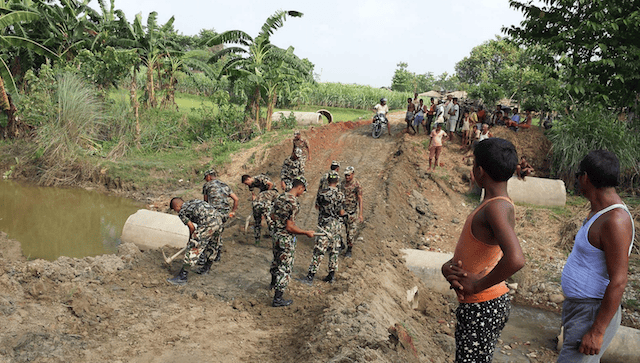 Soldiers of the Nepal Army help rebuild a section of the road in Bara district on Friday that had been washed away by the recent floods.
