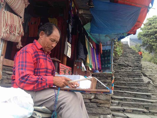 Karma Gurung weaves traditional belts as he waits for customers in Ghandruk on Tuesday.