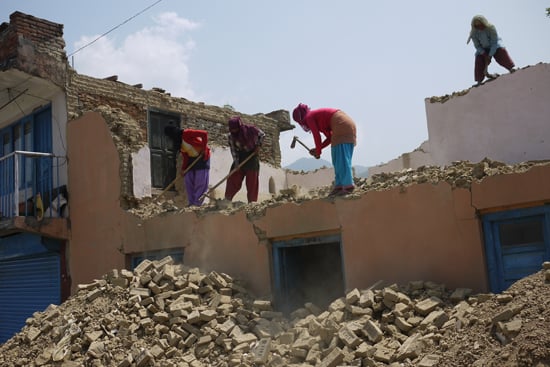 A group of women demolish their own home using farming tools at Chunikhel on Friday.