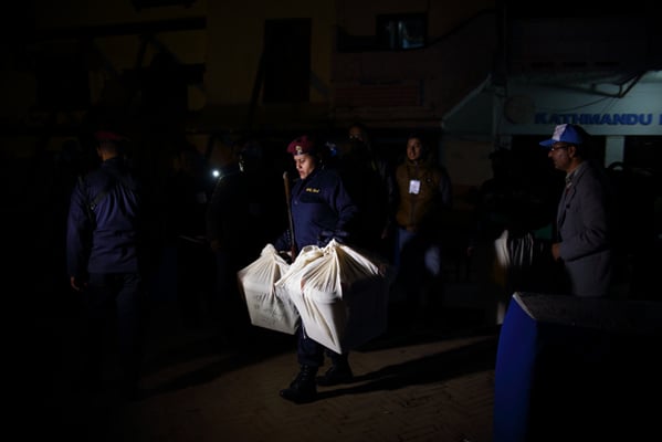 A policewoman carries the sealed ballot boxes to be transported to the collection center after the end of the final phase of parliamentary and provincial elections on Thursday
