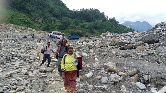 People walk across the Jure landslide area at Sindhupalchok on Thursday. Rain in recent days have brought in debris which has blocked the road.