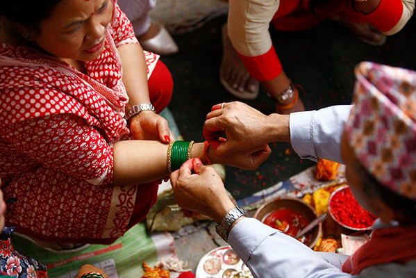 A Hindu priest ties a sacred thread around the wrist of a devotee on the occasion of Janai Purnima (Raksha Bhandan) at Bagalamukhi temple in Lalitpur on Friday.