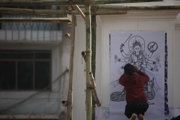 An artist draws a figure of Astamatrika on the wall of Patandhoka on Tuesday.