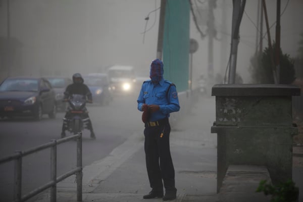 A traffic police covers his face during a dust storm in front of Singha Darbar, Kathmandu on Monday.