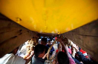 TIE THE KNOT: Devotees under the chariot of God Bhairab fix the chariot during the Bisket festival in Bhaktapur on Wednesday.