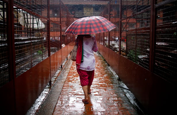 A woman walks past the Krishna temple and Char Narayan temple which are under scaffolding after the 2015 earthquake in Patan Darbar Square on Monday.