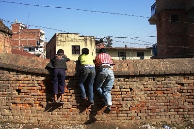LEARNING THRIST: Boys climb up a wall with barbed wires to look into a school in Pulchok on Friday.