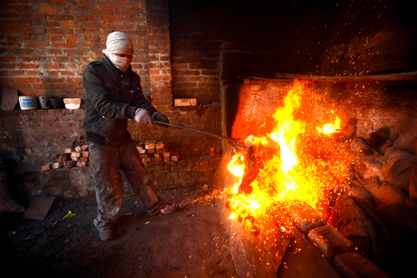 Radheshyam Khadka, 24 heats a wax model of a copper statue at a workshop in Lalitpur on Wednesday